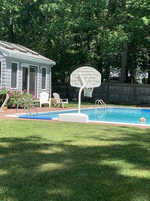 view of pool featuring a lawn, an outdoor structure, fence, and a fenced in pool