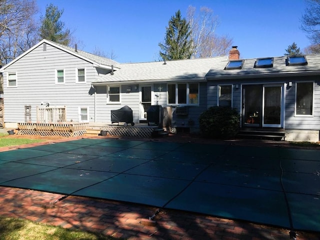 back of house featuring entry steps, a covered pool, and a chimney