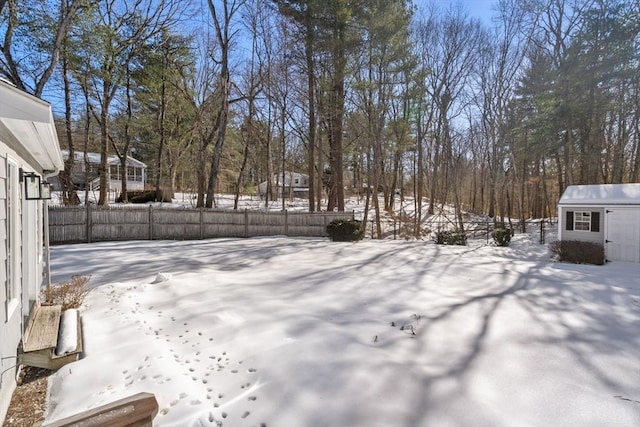 yard covered in snow featuring an outbuilding, a storage unit, and fence