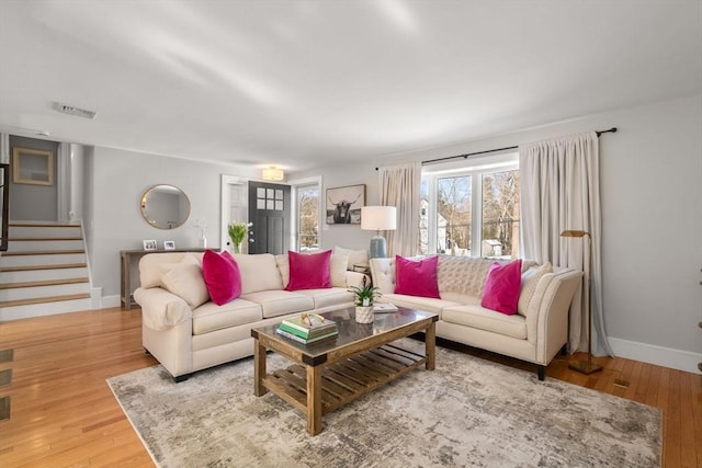 living area featuring hardwood / wood-style floors, stairway, visible vents, and baseboards