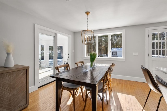 dining space with light wood-type flooring, baseboards, and a chandelier