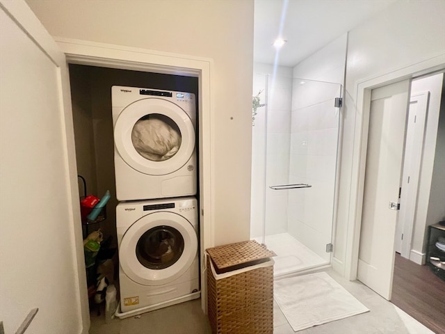 laundry room with hardwood / wood-style floors and stacked washing maching and dryer