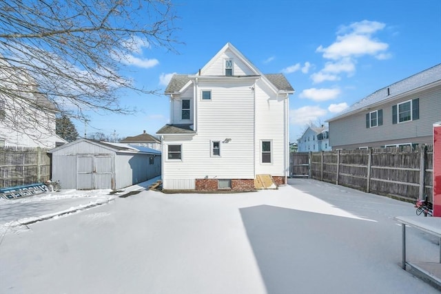 snow covered rear of property featuring a storage unit