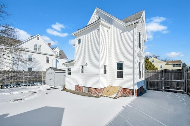 snow covered back of property with a storage unit