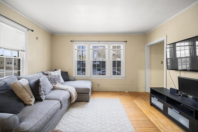 living room with wood-type flooring, a healthy amount of sunlight, and ornamental molding