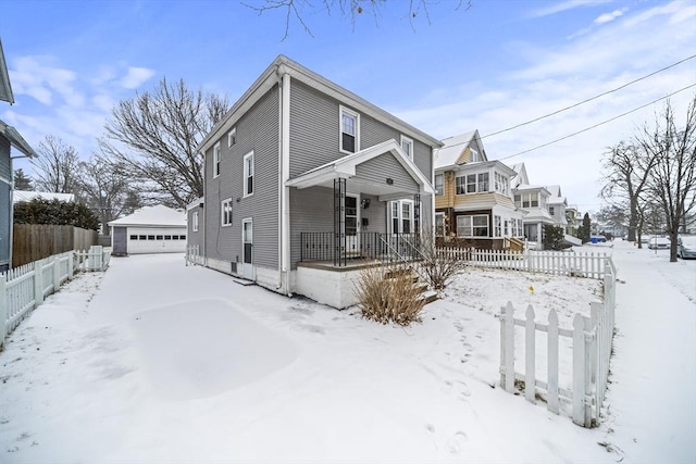 snow covered house featuring a garage and an outdoor structure