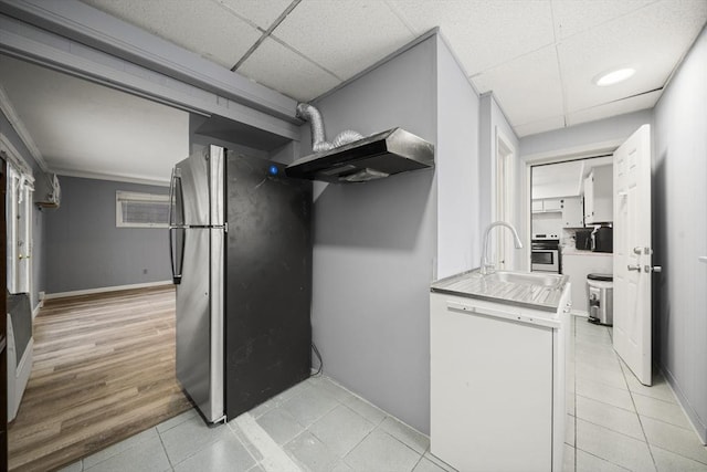 kitchen featuring sink, a drop ceiling, stainless steel fridge, stove, and white cabinets