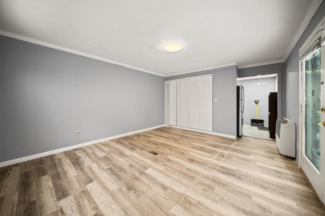 unfurnished bedroom featuring crown molding, light hardwood / wood-style floors, and stainless steel refrigerator