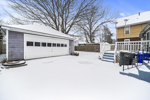 snowy yard featuring a garage and an outbuilding