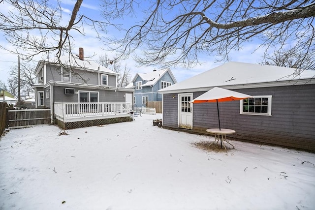 snow covered back of property featuring a deck