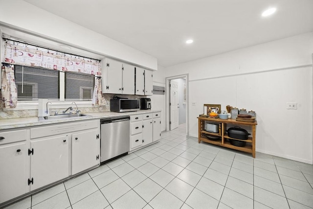 kitchen with appliances with stainless steel finishes, white cabinetry, sink, backsplash, and light tile patterned floors