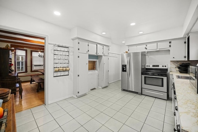 kitchen with light tile patterned flooring, sink, white cabinets, backsplash, and stainless steel appliances