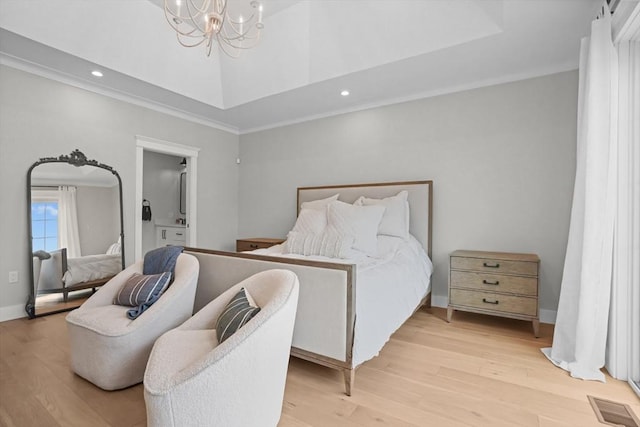 bedroom with a notable chandelier, a raised ceiling, ornamental molding, and light hardwood / wood-style flooring