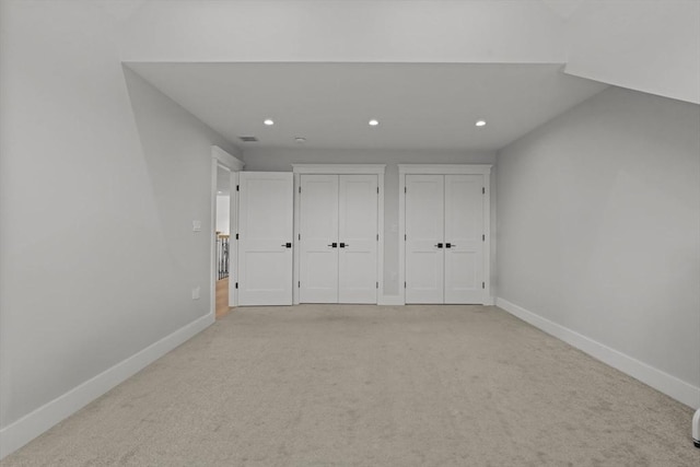 unfurnished bedroom with light carpet and multiple closets