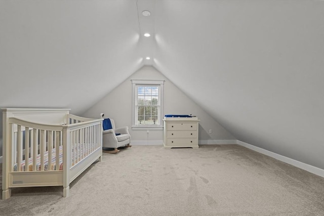 unfurnished bedroom featuring vaulted ceiling, light carpet, and a nursery area