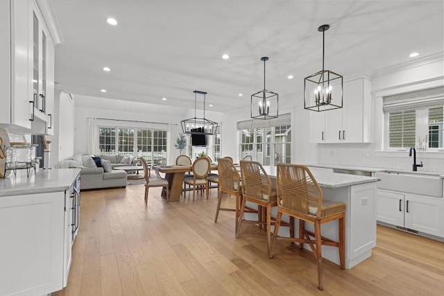 kitchen featuring a center island, white cabinets, decorative light fixtures, and sink