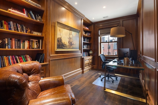 office space with crown molding, dark wood-type flooring, built in shelves, and wood walls