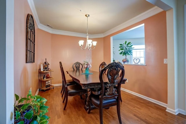 dining space with baseboards, ornamental molding, wood finished floors, and a notable chandelier