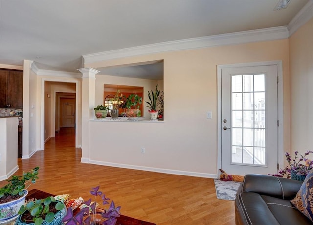 living room with visible vents, light wood finished floors, ornamental molding, and a wealth of natural light