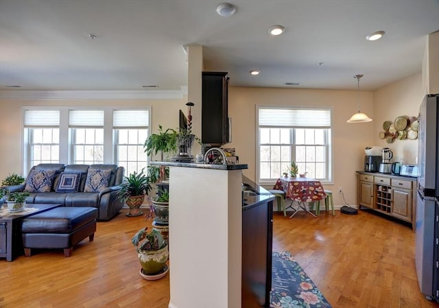 kitchen with light wood-style floors, open floor plan, freestanding refrigerator, dark countertops, and crown molding