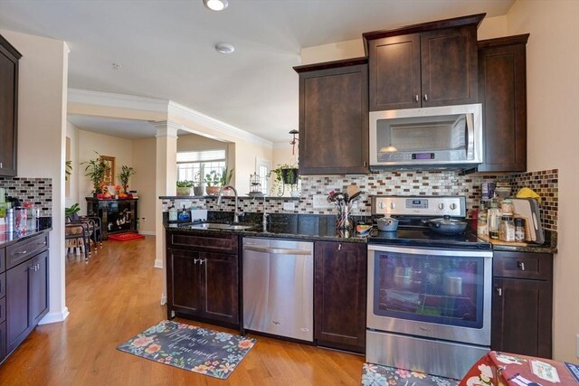 kitchen featuring stainless steel appliances, dark stone counters, a sink, and dark brown cabinetry