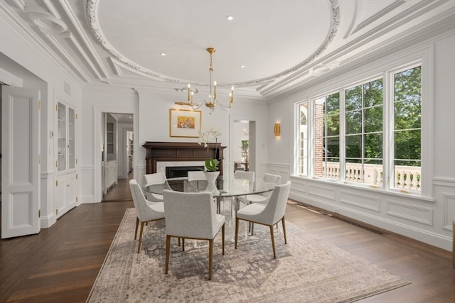 dining space with crown molding, a premium fireplace, a wealth of natural light, and a notable chandelier