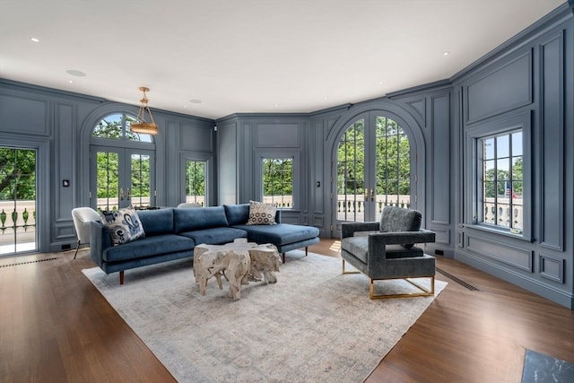 living room with a wealth of natural light, dark wood-type flooring, and french doors