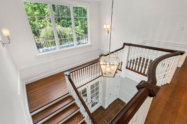 staircase featuring an inviting chandelier and wood-type flooring