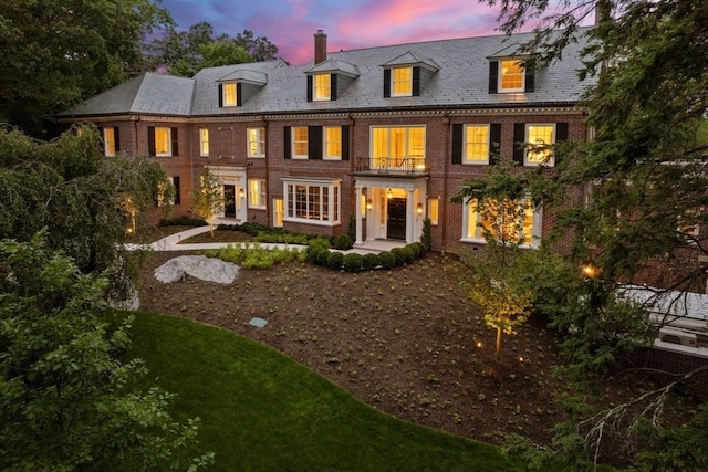 back house at dusk featuring a balcony