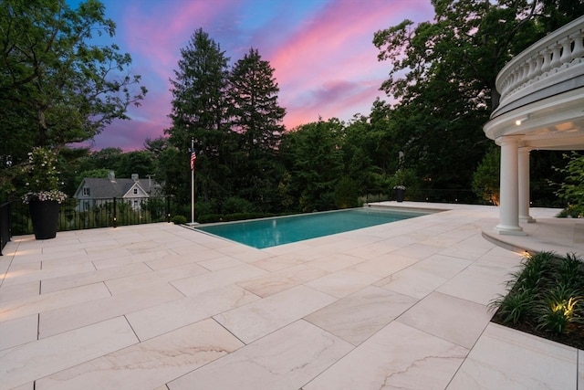 pool at dusk featuring a patio area