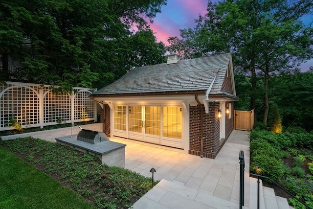 back house at dusk with a patio area