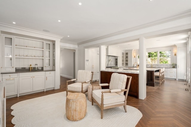 living area featuring crown molding, indoor wet bar, and dark parquet flooring