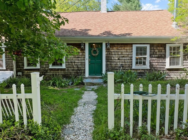 view of front of house featuring fence, a chimney, and a shingled roof