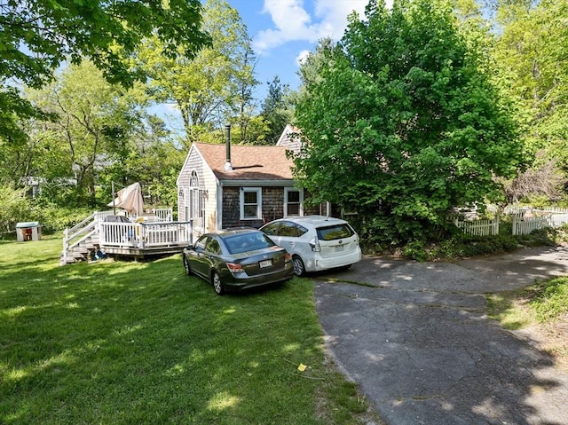 view of front of house with a deck, a shingled roof, stone siding, and asphalt driveway