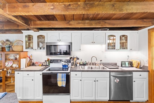 kitchen with appliances with stainless steel finishes, a sink, wood ceiling, beamed ceiling, and white cabinetry