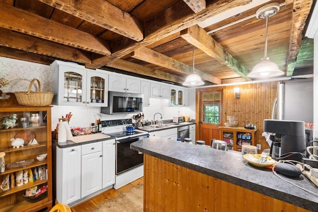 kitchen with stainless steel appliances, light wood-type flooring, a peninsula, dark countertops, and white cabinets
