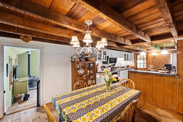 dining room with light wood-style flooring, wood ceiling, a chandelier, beamed ceiling, and wallpapered walls