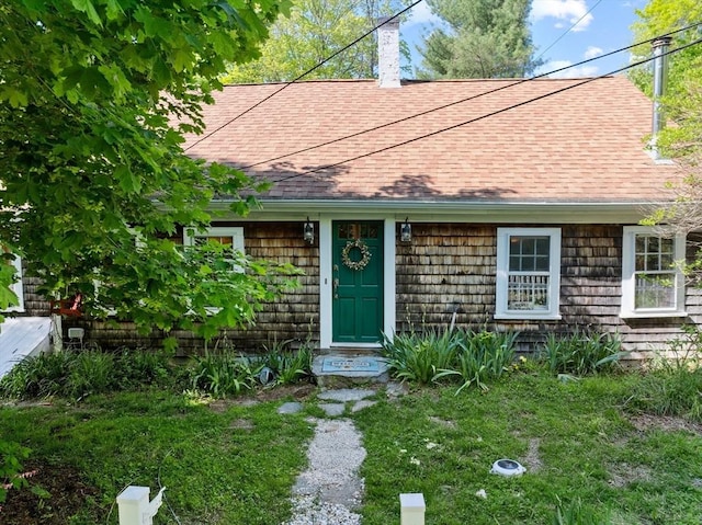 view of exterior entry featuring a shingled roof and a chimney