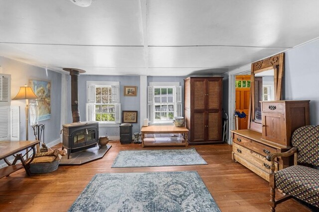 sitting room featuring a wood stove, wood finished floors, and baseboards