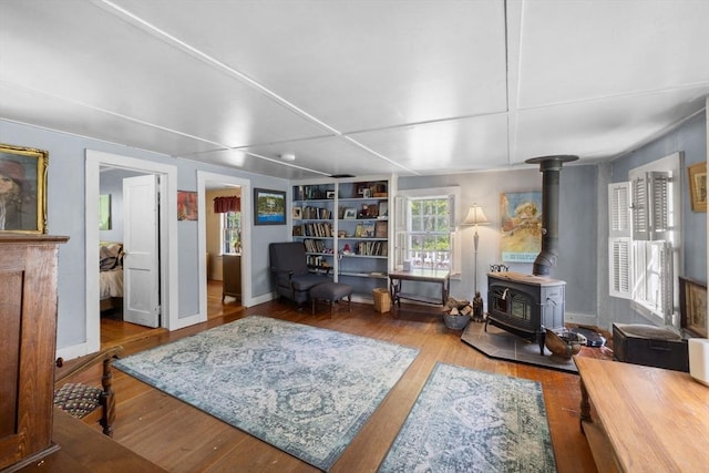 living area featuring a wood stove, wood finished floors, and baseboards