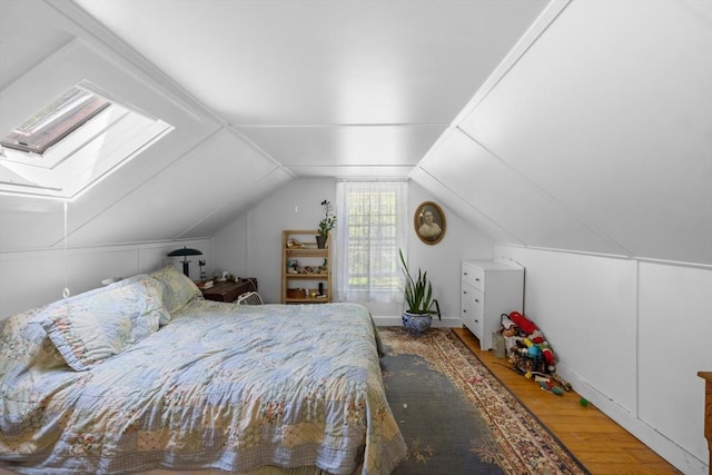 bedroom featuring wood finished floors, vaulted ceiling, and a skylight