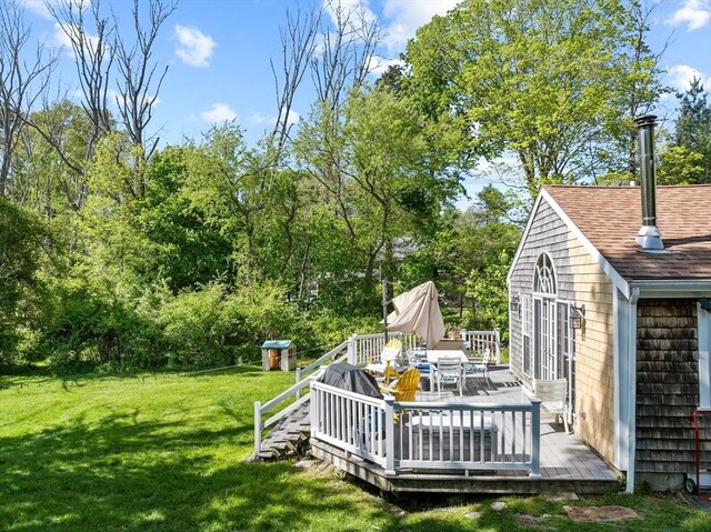 view of green lawn featuring a wooden deck and outdoor dining space
