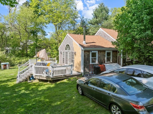 rear view of property featuring a shingled roof, a wooden deck, and a yard