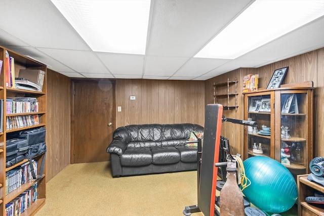 workout room with wooden walls, a drop ceiling, and carpet floors