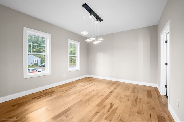 empty room with light hardwood / wood-style flooring and a chandelier