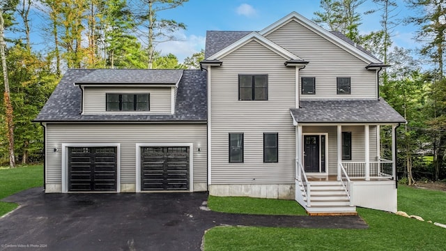 view of front facade with a front lawn, covered porch, and a garage