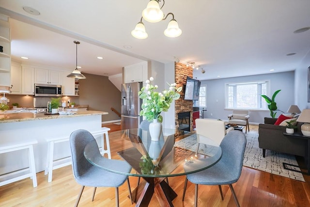 dining area featuring a fireplace, a chandelier, and light hardwood / wood-style flooring