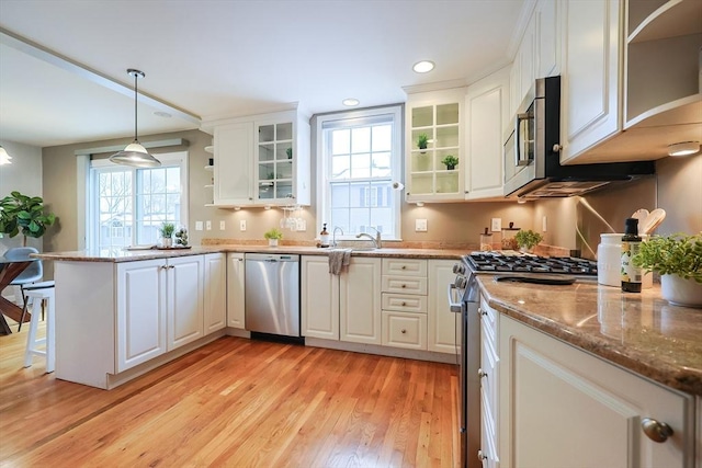 kitchen featuring stone counters, white cabinetry, stainless steel appliances, light hardwood / wood-style flooring, and decorative light fixtures