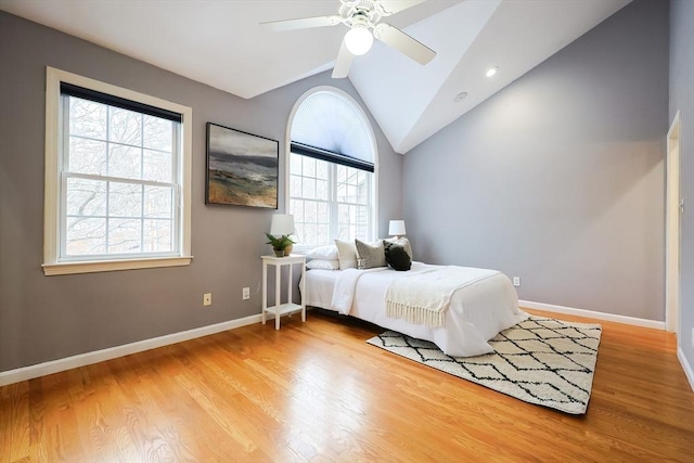 bedroom featuring multiple windows, hardwood / wood-style flooring, vaulted ceiling, and ceiling fan