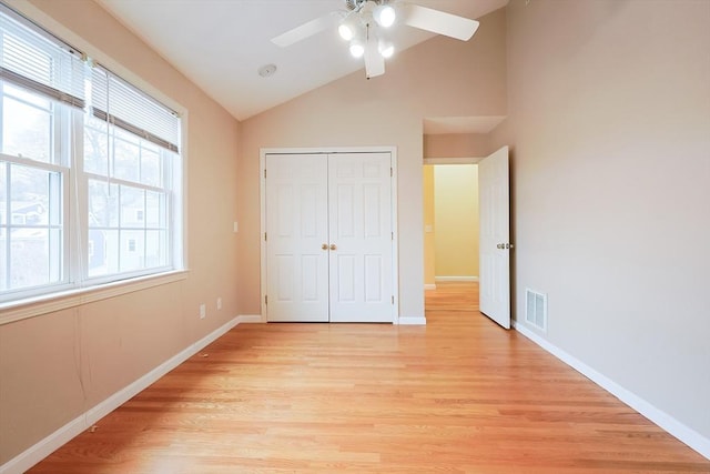 unfurnished bedroom featuring light wood-type flooring, a closet, vaulted ceiling, and ceiling fan